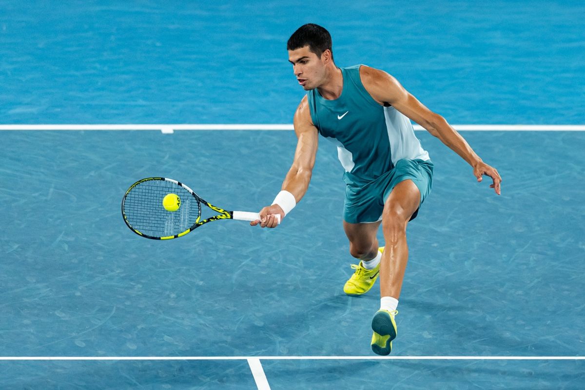 Jan 22, 2025; Melbourne, Victoria, Australia; Carlos Alcaraz of Spain hits a forehand during his match against Novak Djokovic of Serbia in the quarterfinals of the men's singles at the 2025 Australian Open at Melbourne Park. Mandatory Credit: Mike Frey-Imagn Images