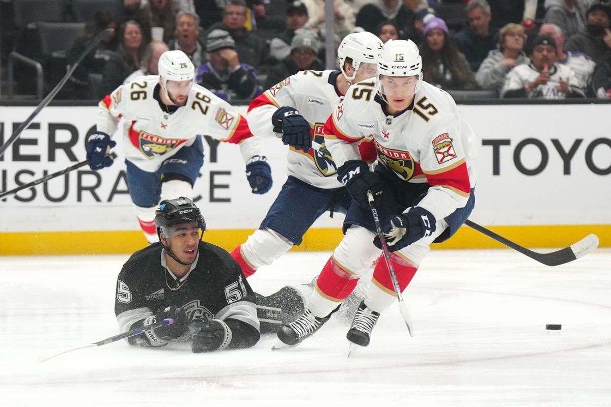 Jan 22, 2025; Los Angeles, California, USA; Florida Panthers center Anton Lundell (15) and LA Kings right wing Quinton Byfield (55) reach for the puck in the second period at Crypto.com Arena. Mandatory Credit: Kirby Lee-Imagn Images
