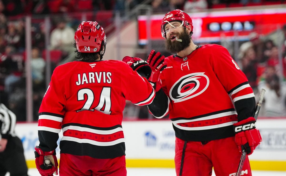 Jan 23, 2025; Raleigh, North Carolina, USA;  Carolina Hurricanes center Seth Jarvis (24) is congratulated by  defenseman Brent Burns (8) after his empty net goal against the Columbus Blue Jackets during the third period at Lenovo Center. Mandatory Credit: James Guillory-Imagn Images