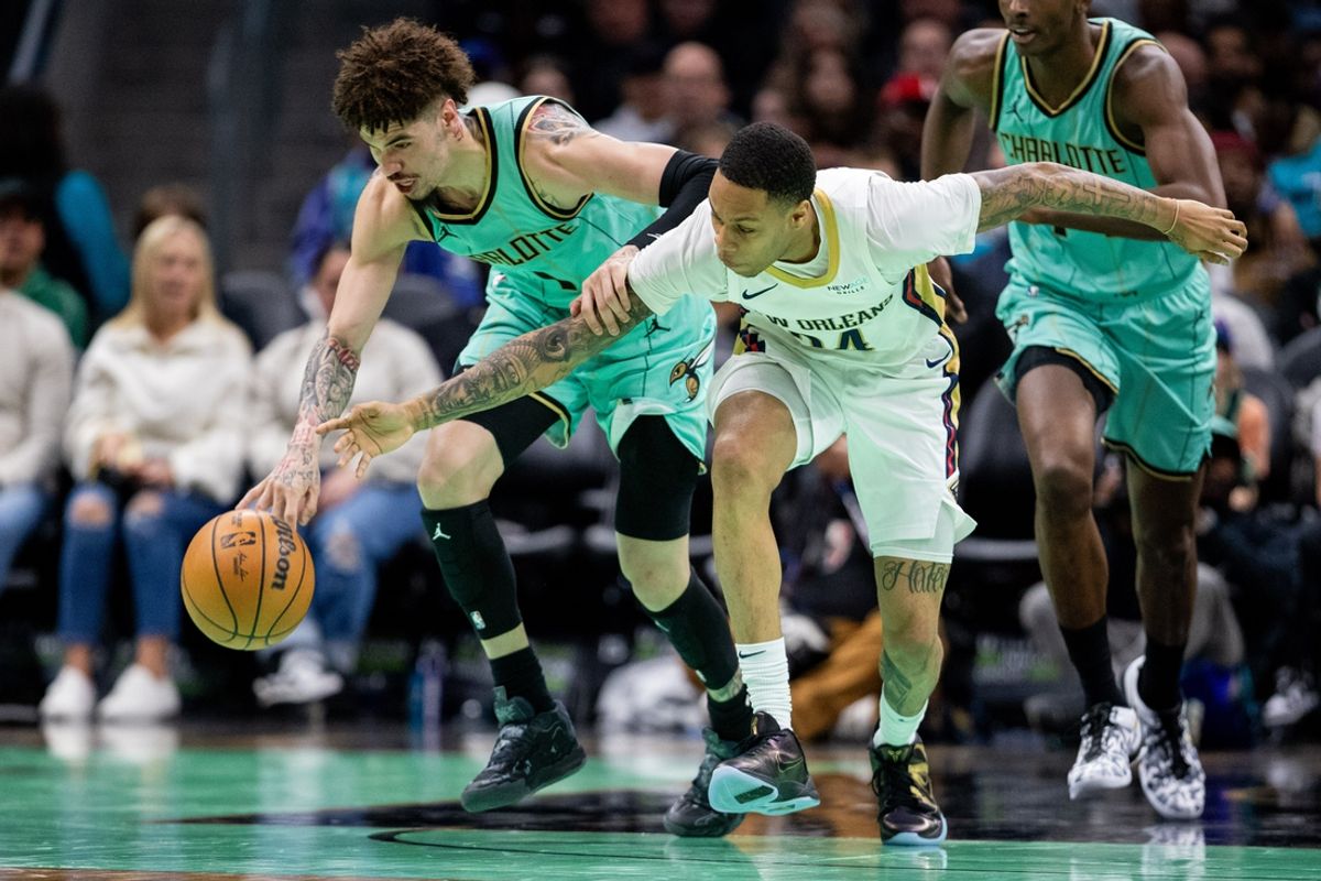 Jan 25, 2025; Charlotte, North Carolina, USA; Charlotte Hornets guard LaMelo Ball (1) and New Orleans Pelicans guard Jordan Hawkins (24) chase a loose ball during the second quarter at Spectrum Center. Mandatory Credit: Scott Kinser-Imagn Images