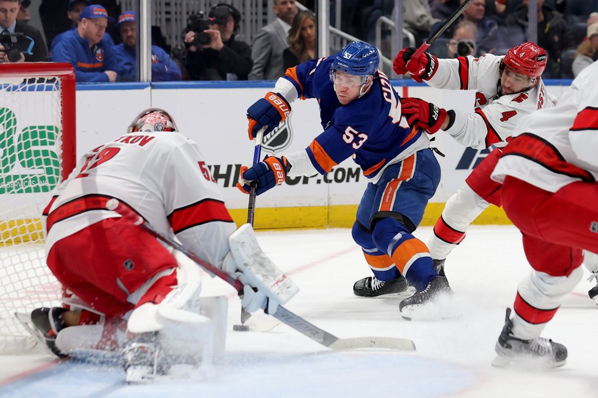 Jan 25, 2025; Elmont, New York, USA; New York Islanders center Casey Cizikas (53) takes a shot against Carolina Hurricanes goaltender Pyotr Kochetkov (52) and defenseman Shayne Gostisbehere (4) during the first period at UBS Arena. Mandatory Credit: Brad Penner-Imagn Images