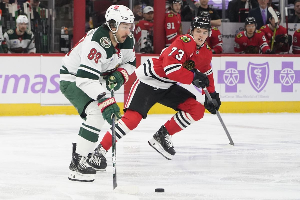 Jan 26, 2025; Chicago, Illinois, USA; Chicago Blackhawks left wing Lukas Reichel (73) defends Minnesota Wild center Frederick Gaudreau (89) during the first period at United Center. Mandatory Credit: David Banks-Imagn Images