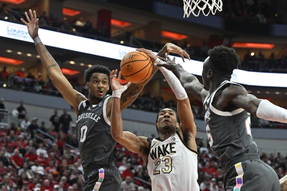 Jan 28, 2025; Louisville, Kentucky, USA;  Wake Forest Demon Deacons guard Hunter Sallis (23) shoots against Louisville Cardinals forward James Scott (0) and forward Aboubacar Traore (25) during the first half at KFC Yum! Center. Mandatory Credit: Jamie Rhodes-Imagn Images