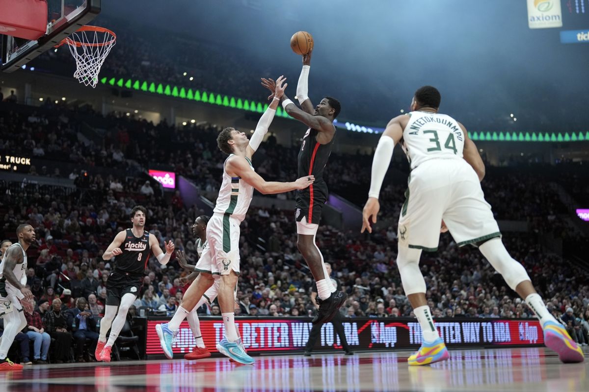 Jan 28, 2025; Portland, Oregon, USA; Portland Trail Blazers center Deandre Ayton (2, right) shoots the ball over Milwaukee Bucks center Brook Lopez (11) during the first half at Moda Center. Mandatory Credit: Soobum Im-Imagn Images