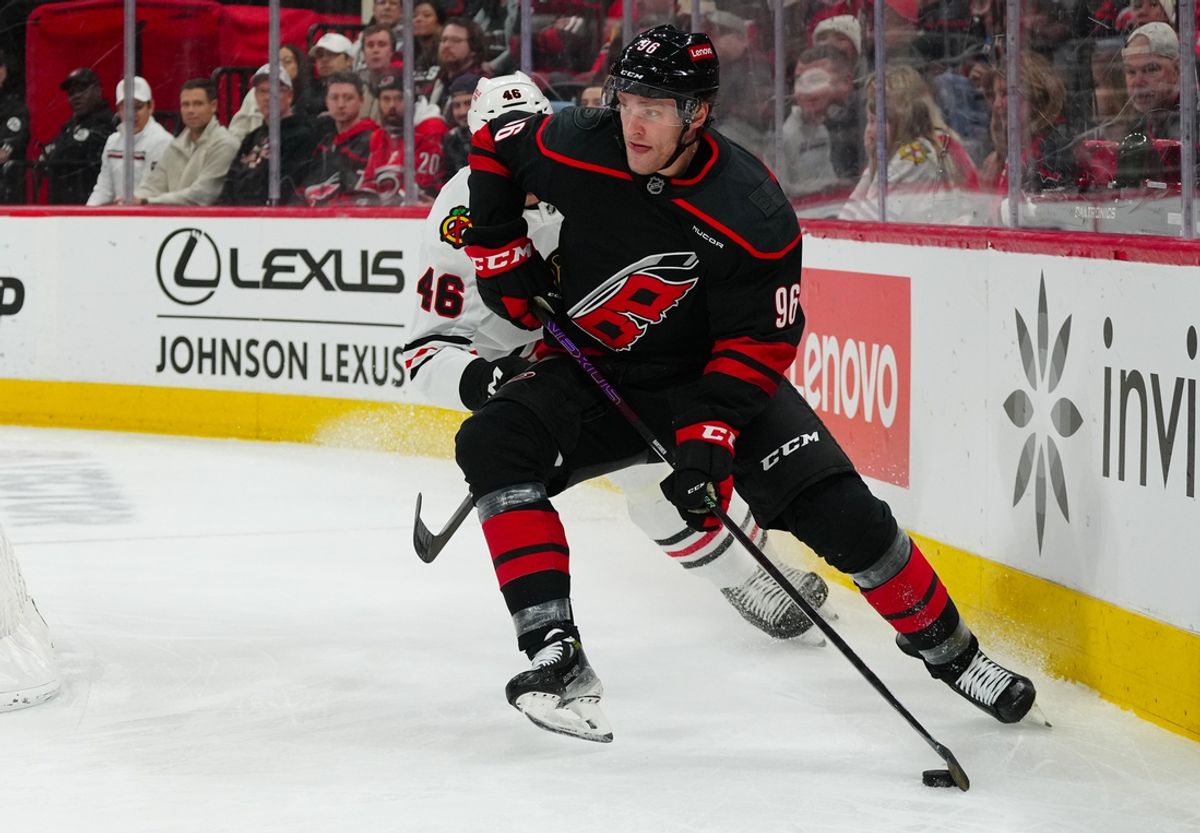 Jan 30, 2025; Raleigh, North Carolina, USA;  Carolina Hurricanes right wing Mikko Rantanen (96) skates with the puck past Chicago Blackhawks defenseman Louis Crevier (46) during the first period at Lenovo Center. Mandatory Credit: James Guillory-Imagn Images