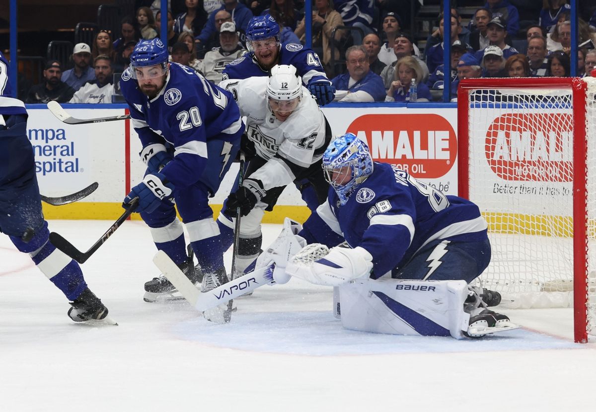 Jan 30, 2025; Tampa, Florida, USA;  Los Angeles Kings left wing Trevor Moore (12) and Tampa Bay Lightning left wing Nick Paul (20) skate for the puck as Tampa Bay Lightning goaltender Andrei Vasilevskiy (88) defends during the second period at Amalie Arena. Mandatory Credit: Kim Klement Neitzel-Imagn Images