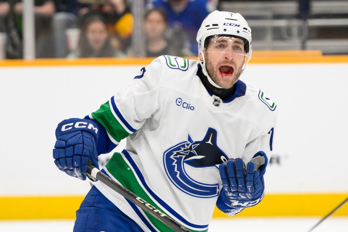 Jan 29, 2025; Nashville, Tennessee, USA;  Vancouver Canucks defenseman Carson Soucy (7) takes a shot to the mouth against the Nashville Predators during the second period at Bridgestone Arena. Mandatory Credit: Steve Roberts-Imagn Images
