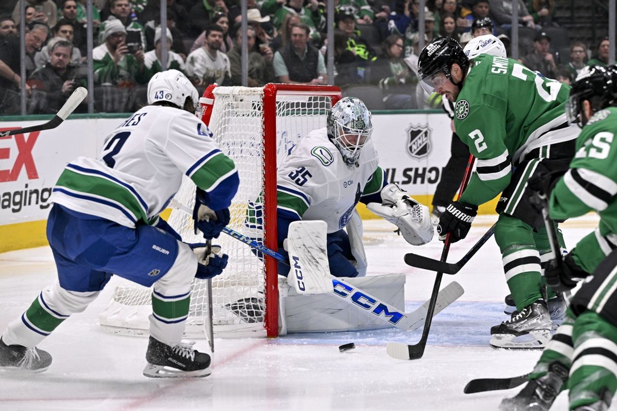 Jan 31, 2025; Dallas, Texas, USA; Vancouver Canucks goaltender Thatcher Demko (35) stops a shot by Dallas Stars defenseman Brendan Smith (2) during the second period at the American Airlines Center. Mandatory Credit: Jerome Miron-Imagn Images