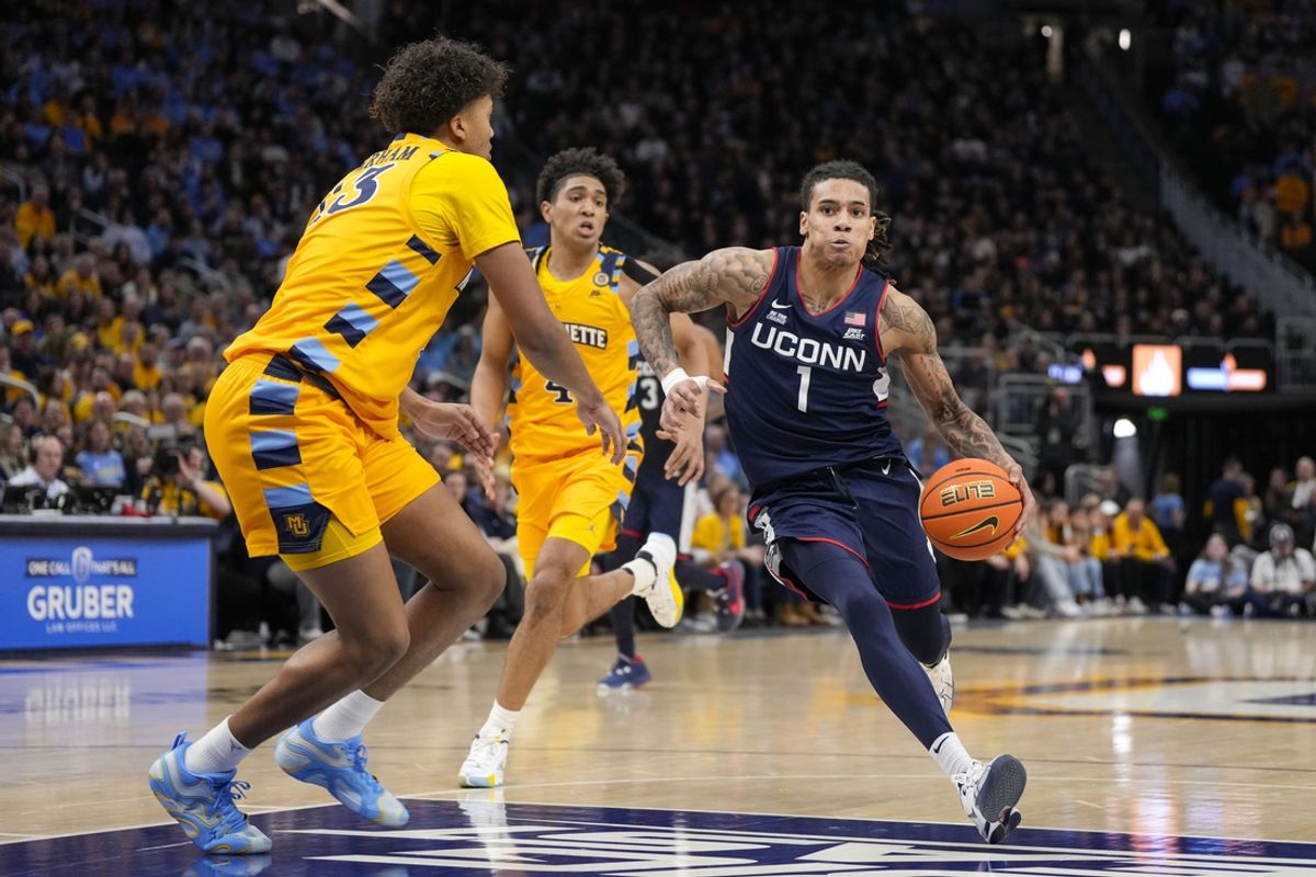 Feb 1, 2025; Milwaukee, Wisconsin, USA;  Connecticut Huskies guard Solo Ball (1) drives for the basket against Marquette Golden Eagles forward Royce Parham (13) during the first half at Fiserv Forum. Mandatory Credit: Jeff Hanisch-Imagn Images