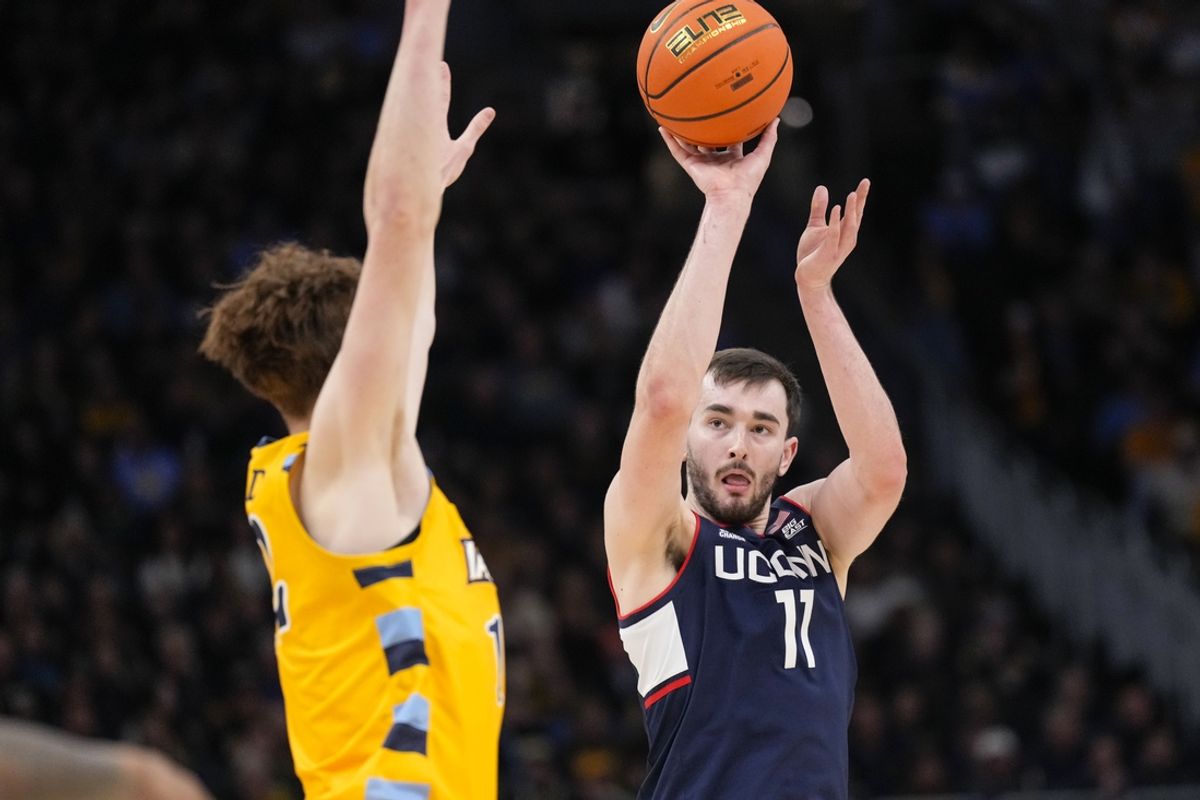 Feb 1, 2025; Milwaukee, Wisconsin, USA;  Connecticut Huskies forward Alex Karaban (11) shoots against Marquette Golden Eagles forward Ben Gold (12) during the first half at Fiserv Forum. Mandatory Credit: Jeff Hanisch-Imagn Images