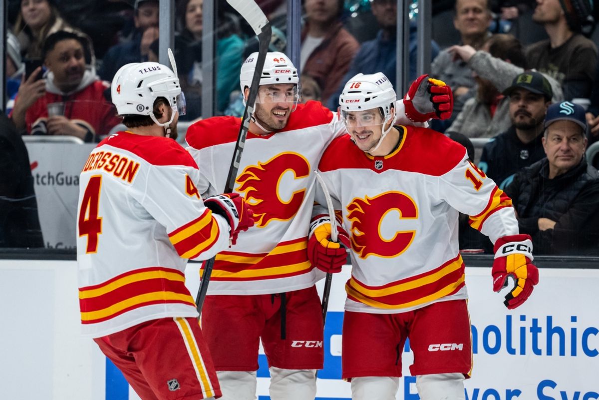 Feb 2, 2025; Seattle, Washington, USA;  Calgary Flames defenseman Rasmus Andersson (4), defenseman Joel Hanley (44) and forward Morgan Frost (16) celebrate a goal during the first period against the Seattle Kraken at Climate Pledge Arena. Mandatory Credit: Stephen Brashear-Imagn Images