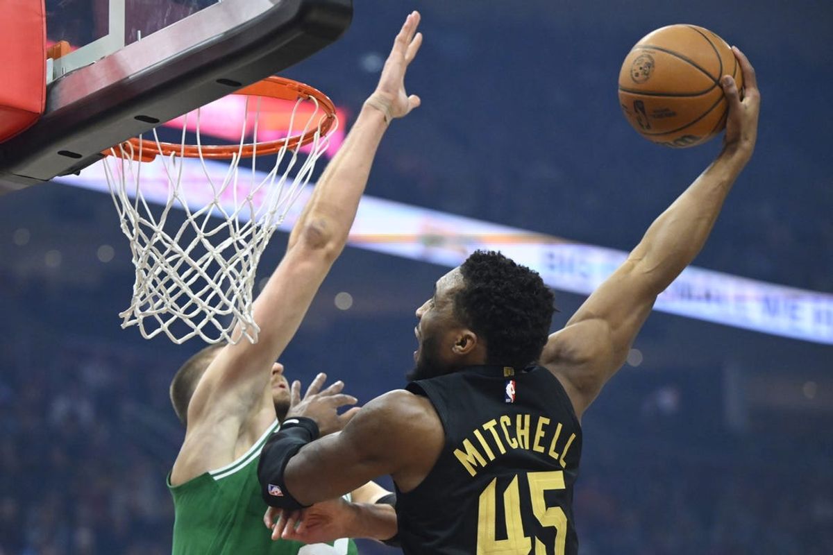 Feb 4, 2025; Cleveland, Ohio, USA; Cleveland Cavaliers guard Donovan Mitchell (45) dunks beside Boston Celtics center Kristaps Porzingis (8) in the first quarter at Rocket Mortgage FieldHouse. Mandatory Credit: David Richard-Imagn Images