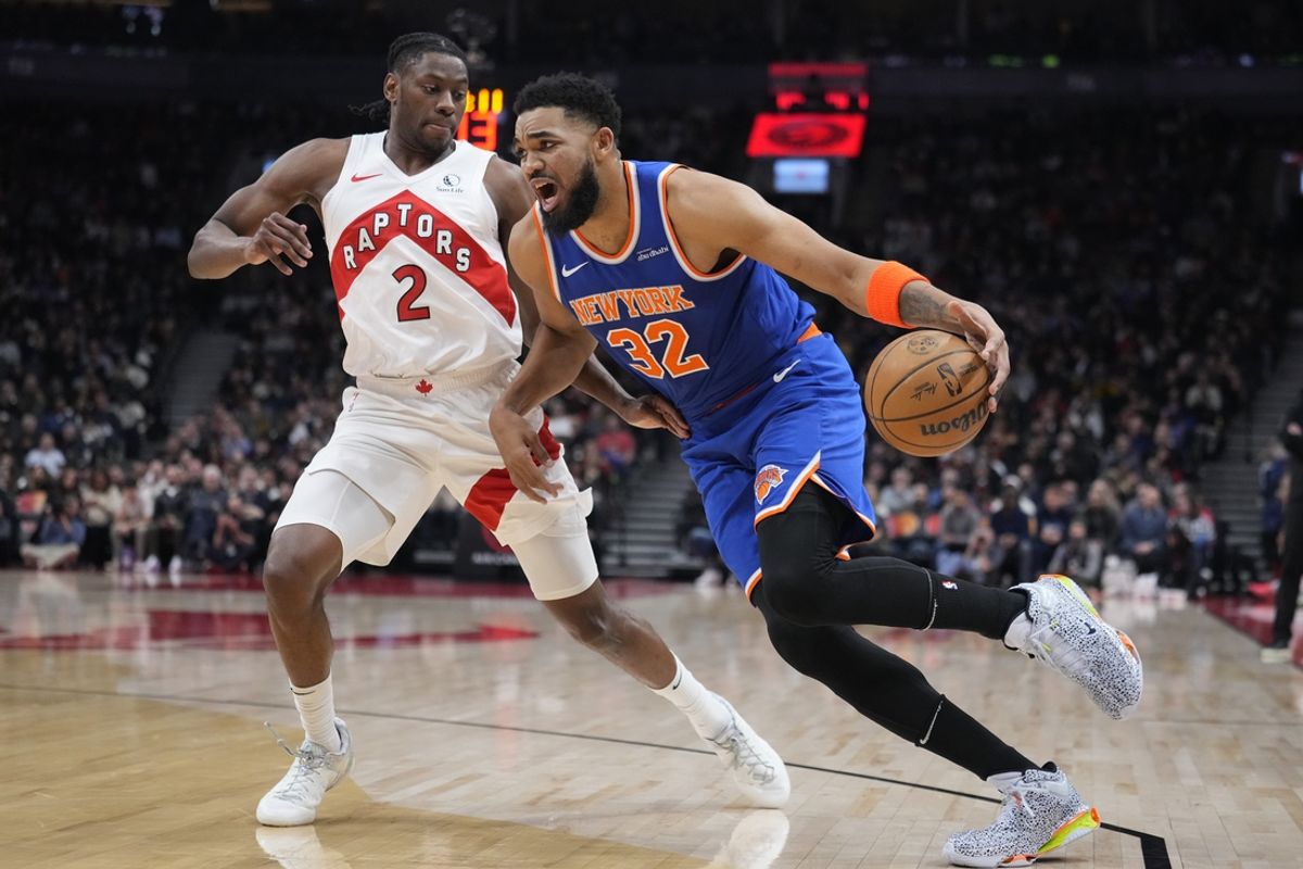 Feb 4, 2025; Toronto, Ontario, CAN; New York Knicks center Karl-Anthony Towns (32)  drives to the net against Toronto Raptors forward Jonathon Mogbo (2) during the first half at Scotiabank Arena. Mandatory Credit: John E. Sokolowski-Imagn Images