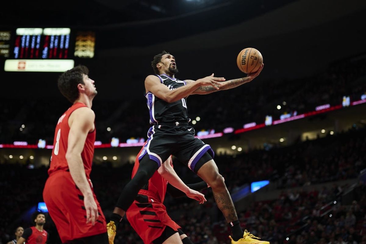 Feb 6, 2025; Portland, Oregon, USA; Sacramento Kings guard Malik Monk (0) drives to the basket during the first half against Portland Trail Blazers center Donovan Clingan (23) and forward Deni Avdija (8) at Moda Center. Mandatory Credit: Troy Wayrynen-Imagn Images