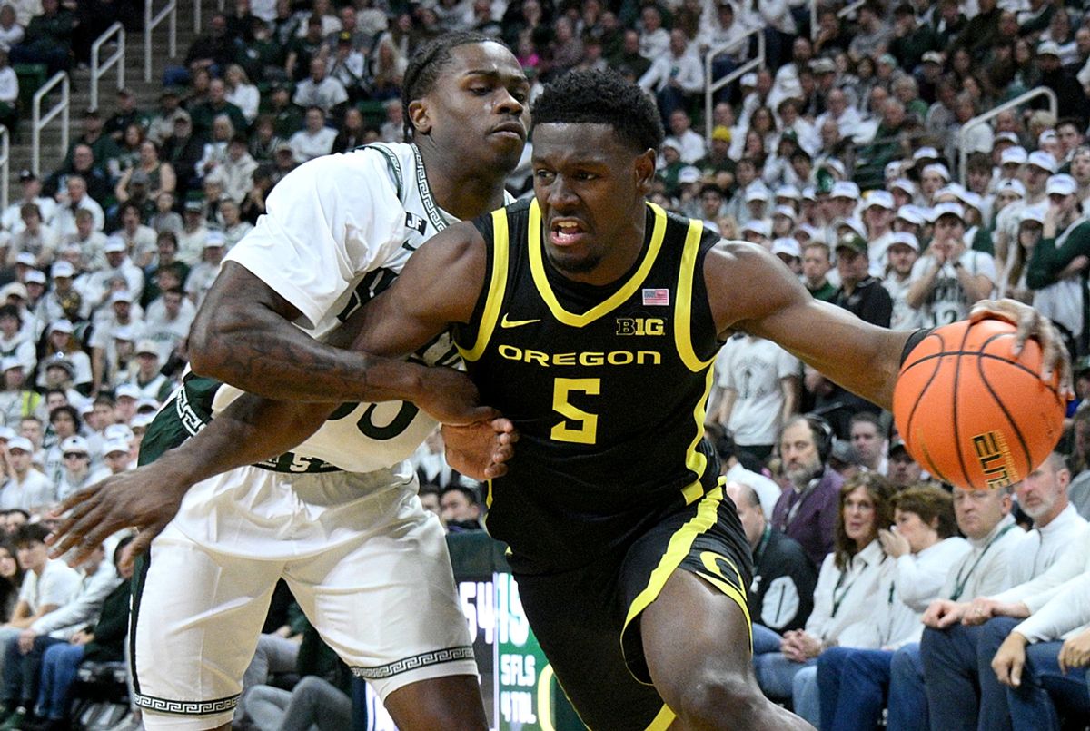 Feb 8, 2025; East Lansing, Michigan, USA;  Oregon Ducks guard TJ Bamba (5) drives against Michigan State Spartans forward Coen Carr (55) during the first half at Jack Breslin Student Events Center. Mandatory Credit: Dale Young-Imagn Images