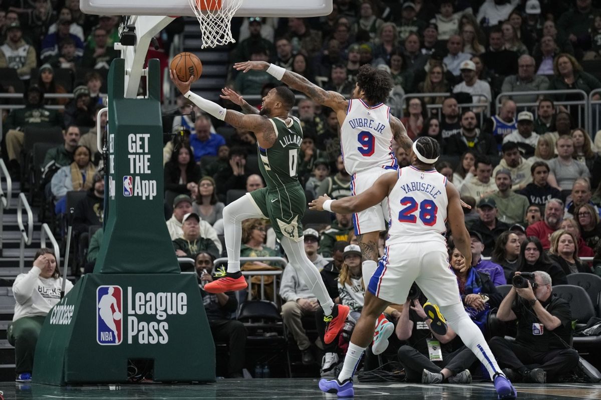 Feb 9, 2025; Milwaukee, Wisconsin, USA;  Milwaukee Bucks guard Damian Lillard (0) shoots against Philadelphia 76ers forward Kelly Oubre Jr. (9) during the second quarter at Fiserv Forum. Mandatory Credit: Jeff Hanisch-Imagn Images
