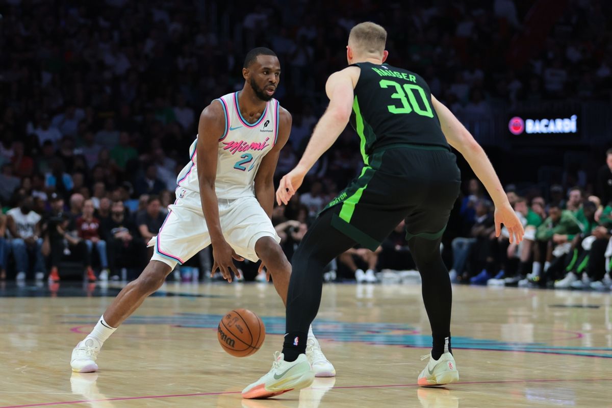 Feb 10, 2025; Miami, Florida, USA; Miami Heat forward Andrew Wiggins (22) dribbles the basketball as Boston Celtics forward Sam Hauser (30) defends during the second quarter at Kaseya Center. Mandatory Credit: Sam Navarro-Imagn Images