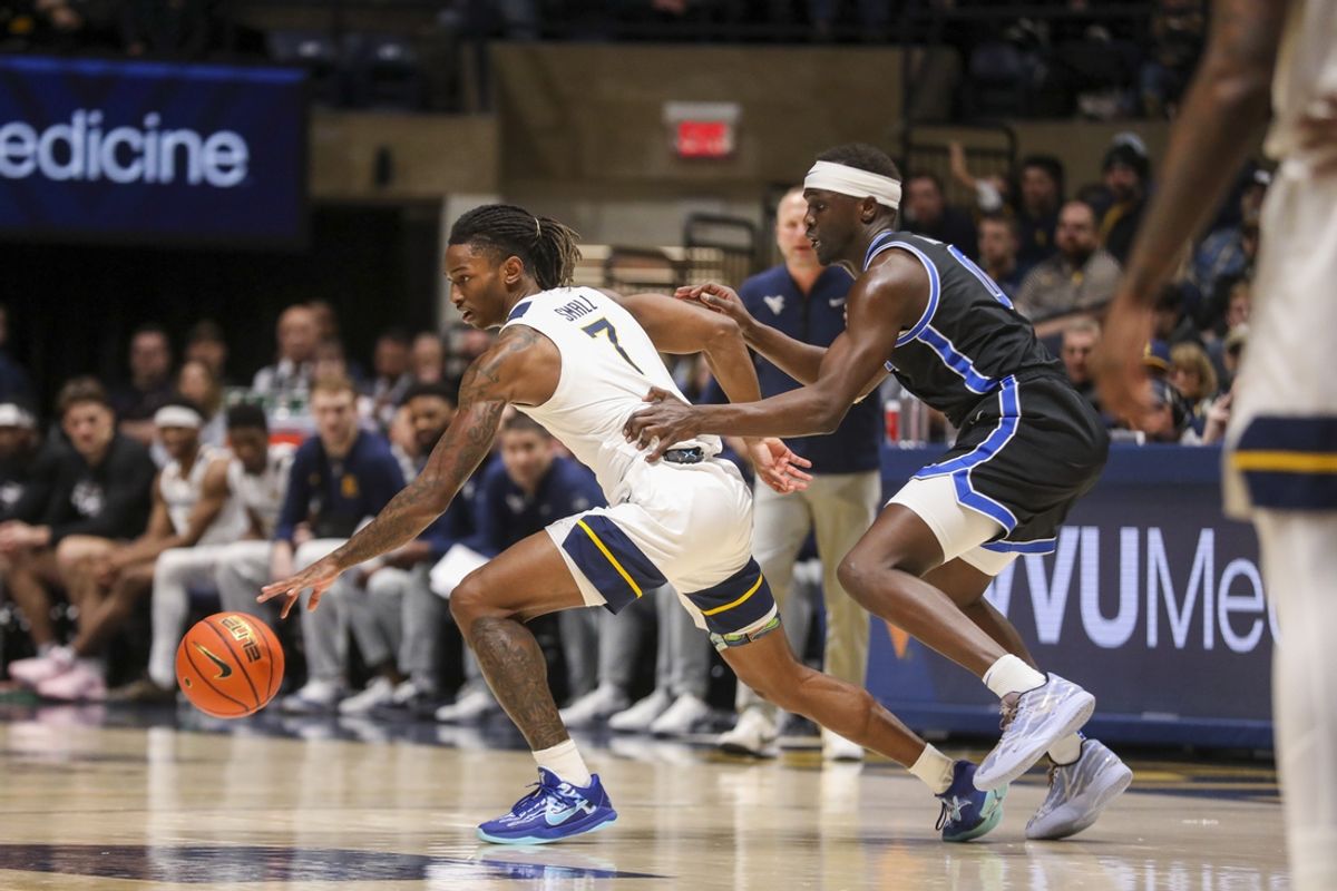 Feb 11, 2025; Morgantown, West Virginia, USA; West Virginia Mountaineers guard Javon Small (7) dribbles while defended by Brigham Young Cougars forward Mawot Mag (0) during the first half at WVU Coliseum. Mandatory Credit: Ben Queen-Imagn Images