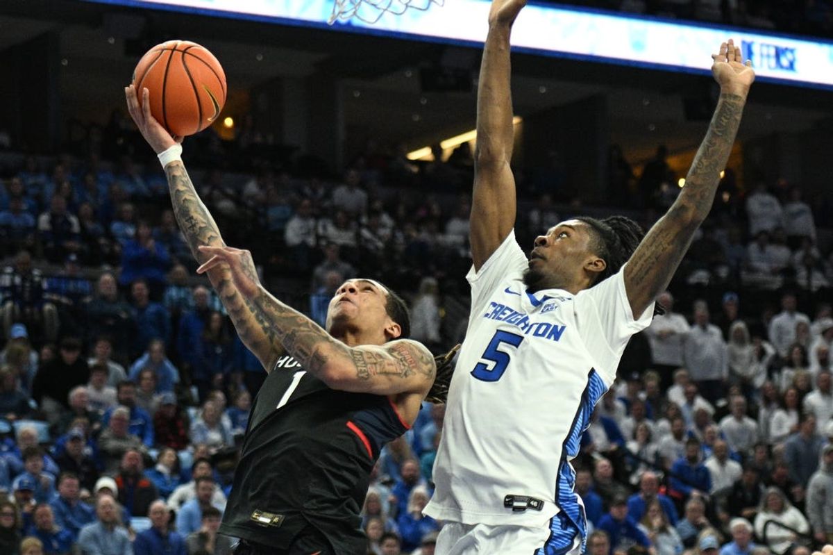 Feb 11, 2025; Omaha, Nebraska, USA;  Connecticut Huskies guard Solo Ball (1) drives against Creighton Bluejays guard Jamiya Neal (5) during the first half at CHI Health Center Omaha. Mandatory Credit: Steven Branscombe-Imagn Images