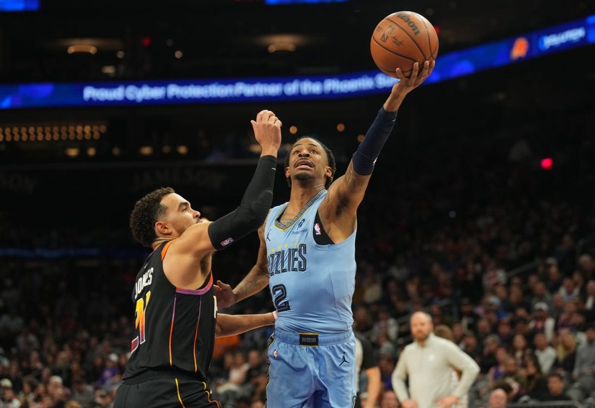 Feb 11, 2025; Phoenix, Arizona, USA; Memphis Grizzlies guard Ja Morant (12) drives against Phoenix Suns guard Tyus Jones (21) during the second half at Footprint Center. Mandatory Credit: Joe Camporeale-Imagn Images