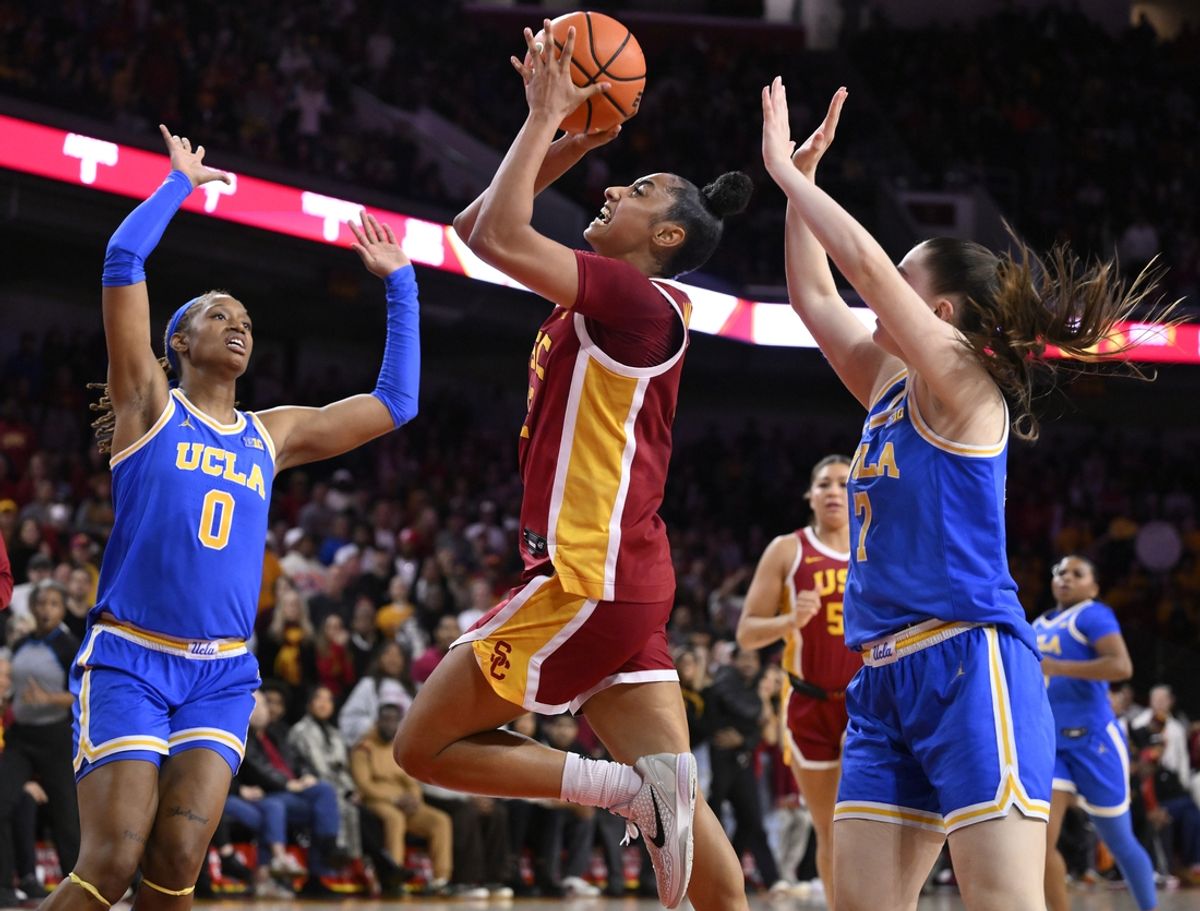 Feb 13, 2025; Los Angeles, California, USA; USC Trojans guard JuJu Watkins (12) drives to the basket between UCLA Bruins forward Janiah Barker (0) and guard Elina Aarnisalo (7) during the fourth quarter at Galen Center. Mandatory Credit: Robert Hanashiro-Imagn Images