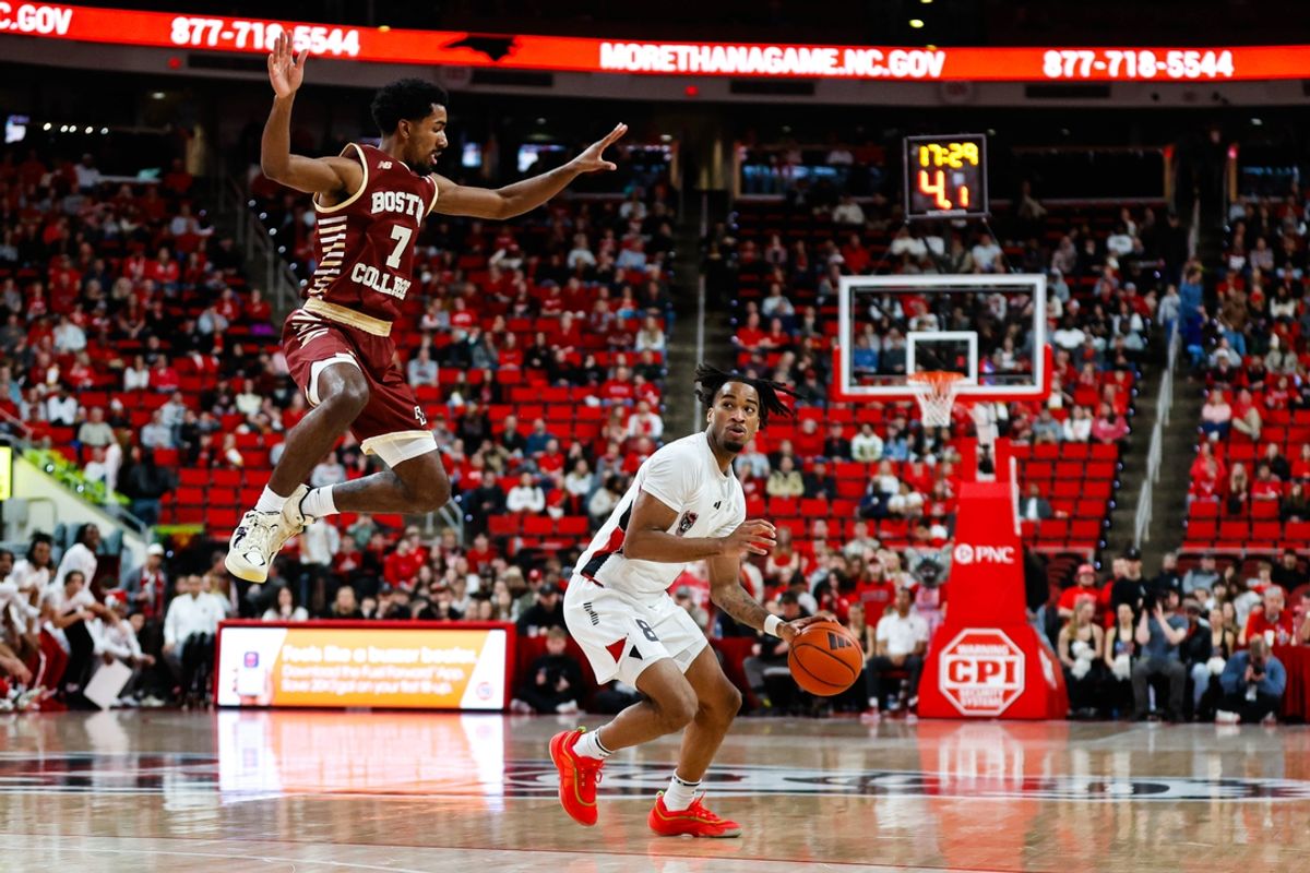 Feb 15, 2025; Raleigh, North Carolina, USA; North Carolina State Wolfpack guard Jayden Taylor (8) holds the ball while Boston College Eagles guard Joshua Beadle (7) jumps mid air during the first half of the game at Lenovo Center. Mandatory Credit: Jaylynn Nash-Imagn Images