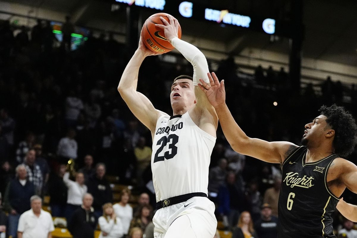 Feb 15, 2025; Boulder, Colorado, USA; Colorado Buffaloes forward Andrej Jakimovski (23) grabs a rebound away from UCF Knights guard Dallan Coleman (6) in the first half at the CU Events Center. Mandatory Credit: Ron Chenoy-Imagn Images