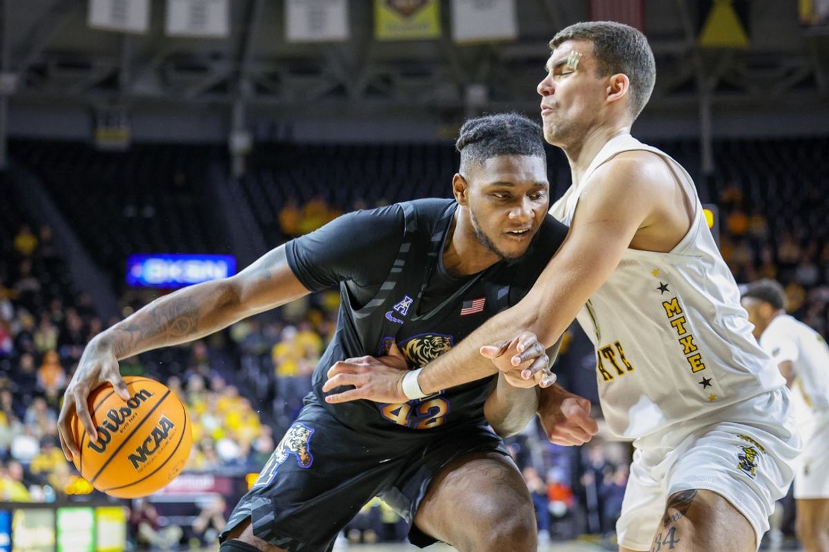 Feb 16, 2025; Wichita, Kansas, USA; Memphis Tigers forward Dain Dainja (42) drives to the basket around Wichita State Shockers forward Ronnie DeGray III (3) during the first half at Charles Koch Arena. Mandatory Credit: William Purnell-Imagn Images