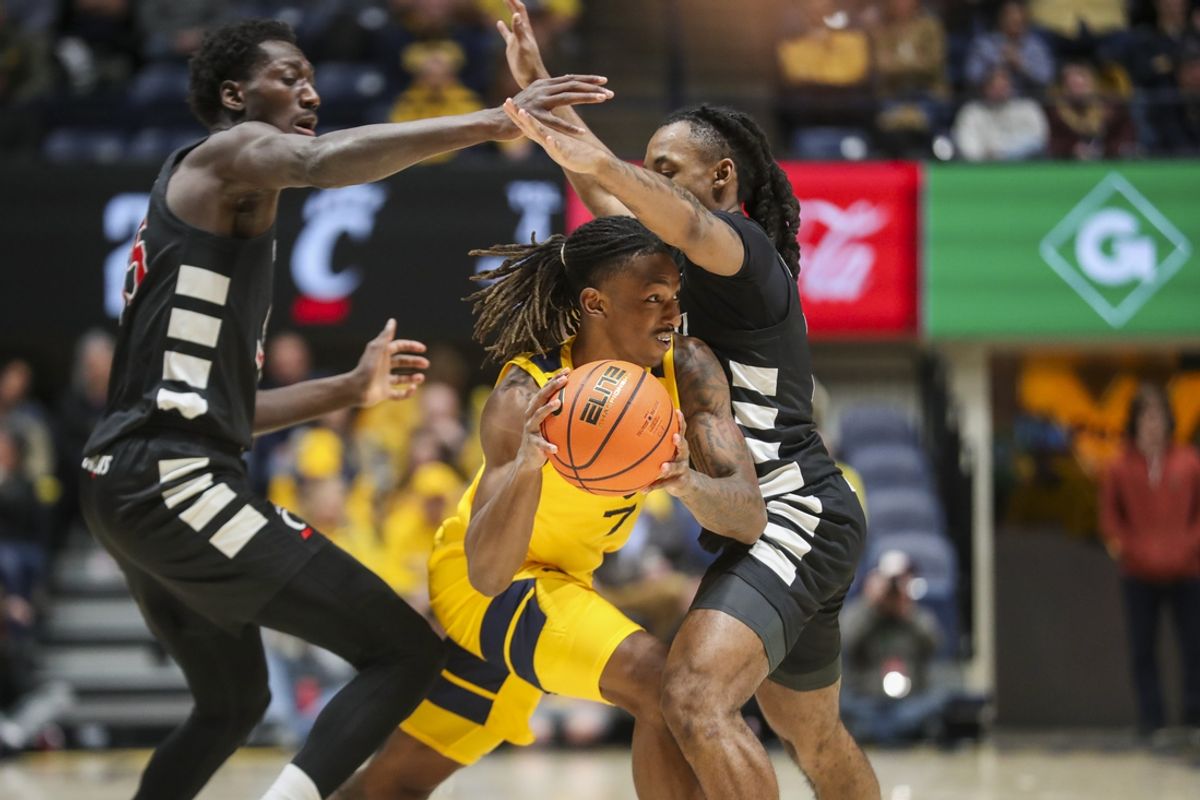 Feb 19, 2025; Morgantown, West Virginia, USA; West Virginia Mountaineers guard Javon Small (7) controls the ball against Cincinnati Bearcats forward Aziz Bandaogo (55) and guard Day Day Thomas (1) during the first half at WVU Coliseum. Mandatory Credit: Ben Queen-Imagn Images
