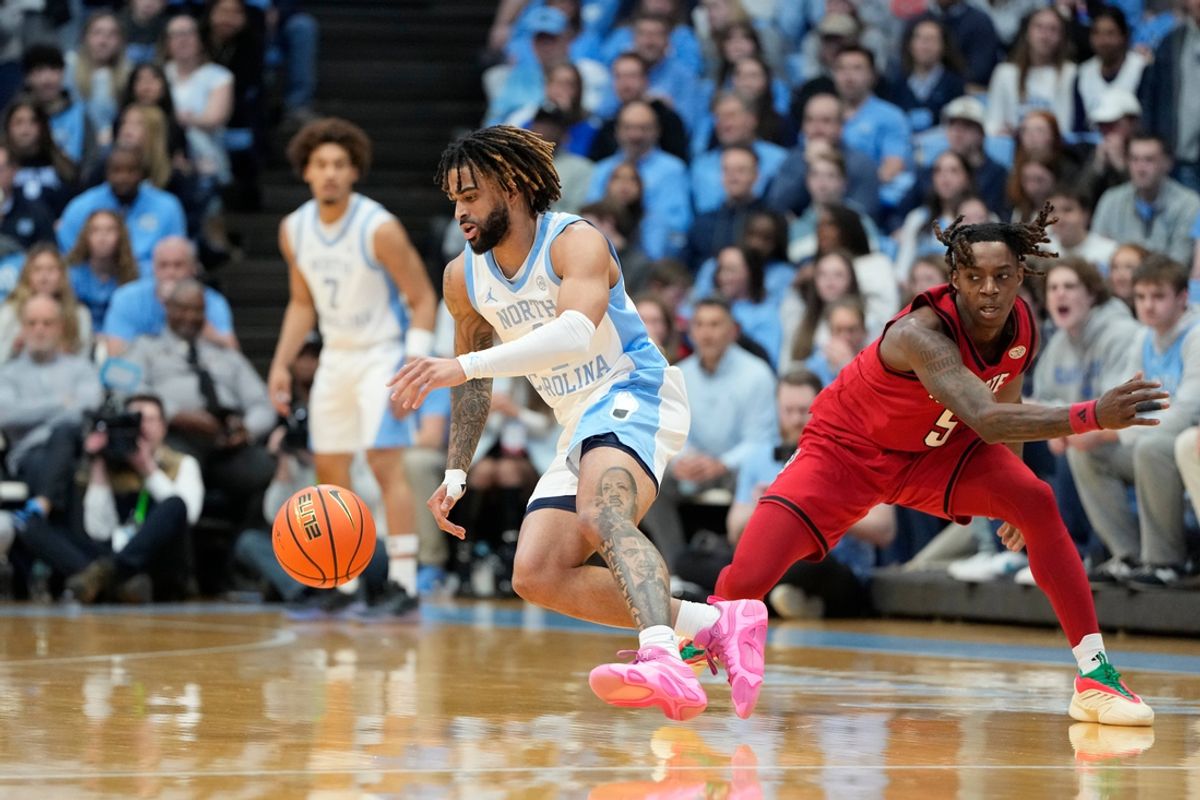 Feb 19, 2025; Chapel Hill, North Carolina, USA; North Carolina Tar Heels guard RJ Davis (4) dribbles as North Carolina State Wolfpack guard Trey Parker (5) defends in the first half at Dean E. Smith Center. Mandatory Credit: Bob Donnan-Imagn Images