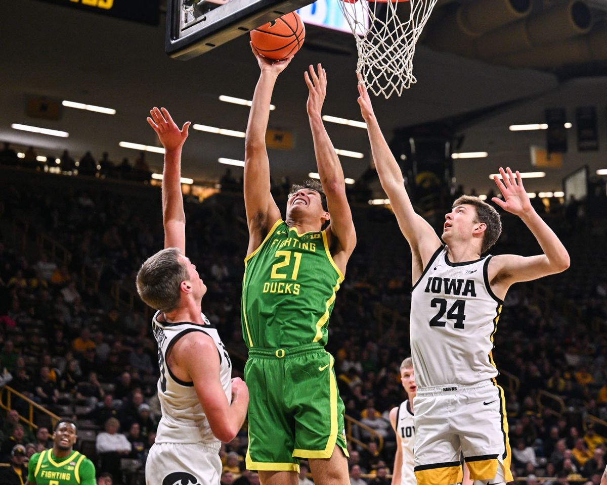 Feb 19, 2025; Iowa City, Iowa, USA; Oregon Ducks forward Brandon Angel (21) goes to the basket as Iowa Hawkeyes forward Pryce Sandfort (24) and forward Payton Sandfort (20) defend during the first half at Carver-Hawkeye Arena. Mandatory Credit: Jeffrey Becker-Imagn Images