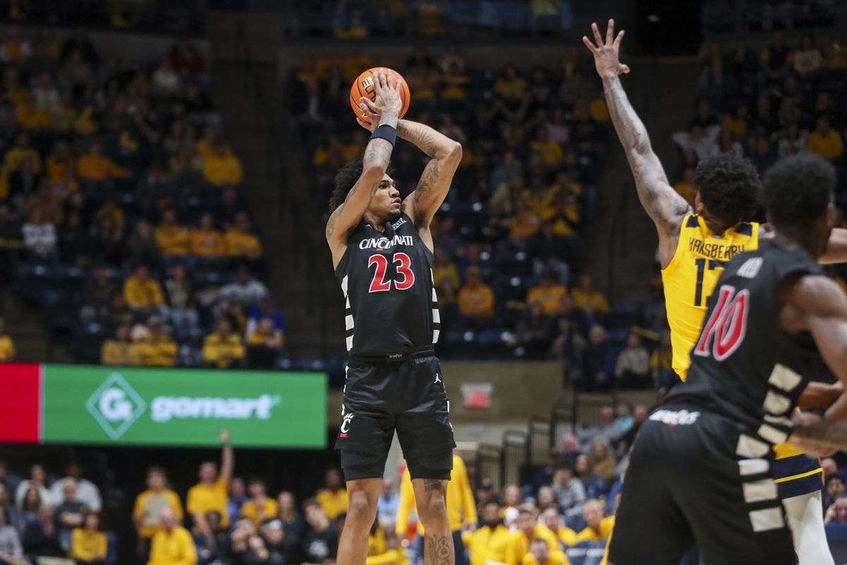 Feb 19, 2025; Morgantown, West Virginia, USA; Cincinnati Bearcats forward Dillon Mitchell (23) shoots a three point shot over West Virginia Mountaineers forward Amani Hansberry (13) during the second half at WVU Coliseum. Mandatory Credit: Ben Queen-Imagn Images