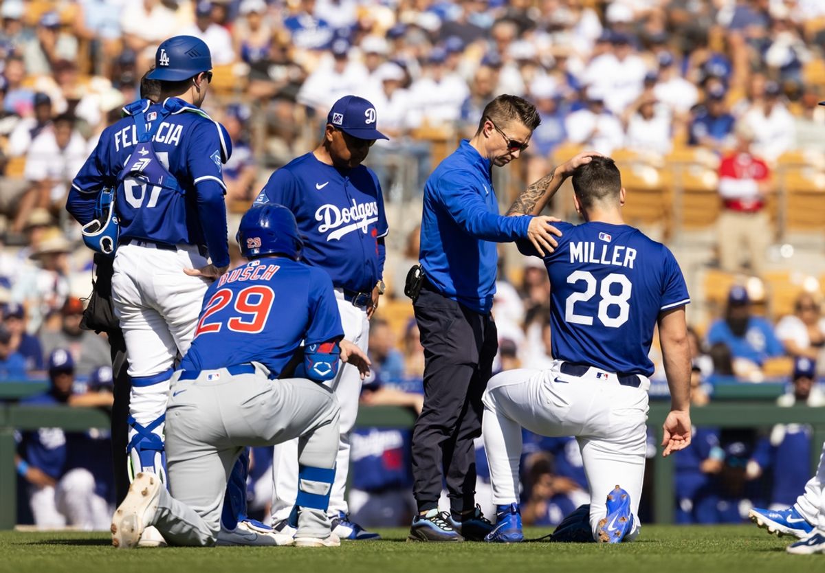 Feb 20, 2025; Phoenix, Arizona, USA; Los Angeles Dodgers pitcher Bobby Miller (28) is tended to by a trainer after being hit in the head with a line drive against the Chicago Cubs during a spring training game at Camelback Ranch-Glendale. Mandatory Credit: Mark J. Rebilas-Imagn Images