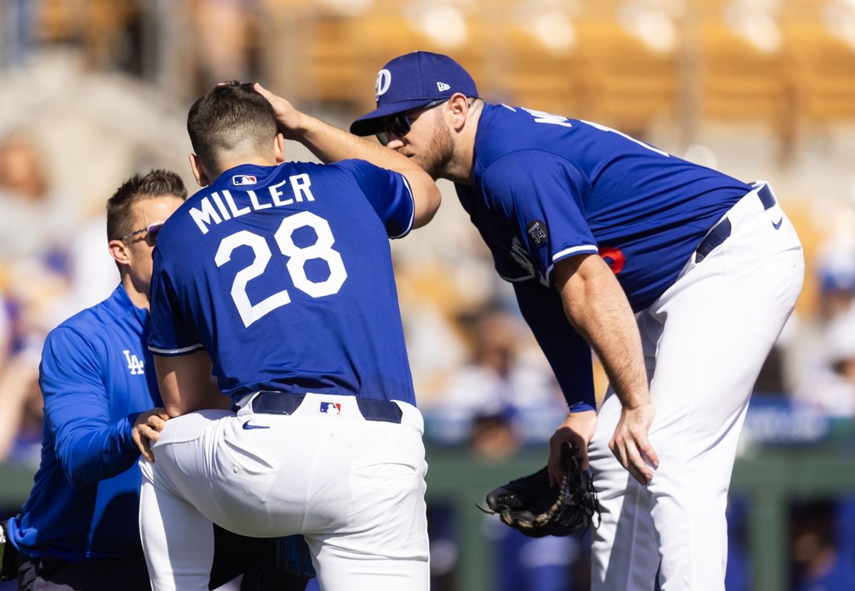 Feb 20, 2025; Phoenix, Arizona, USA; Los Angeles Dodgers pitcher Bobby Miller (28) talks to Max Muncy as he is tended to by a trainer after being hit in the head with a line drive against the Chicago Cubs during a spring training game at Camelback Ranch-Glendale. Mandatory Credit: Mark J. Rebilas-Imagn Images