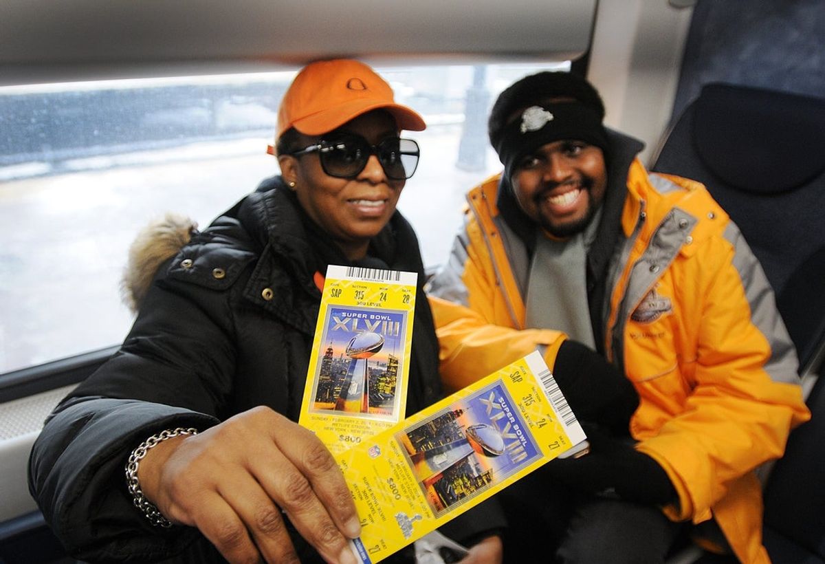 Passengers Renee Cassell (L) of Brooklyn and her Godson Pierre Percy of New Windsor, show their Super Bowl tickets on the way to on their way to Meadowlands Station for the Super Bowl at MetLife Stadium in East Rutherford.