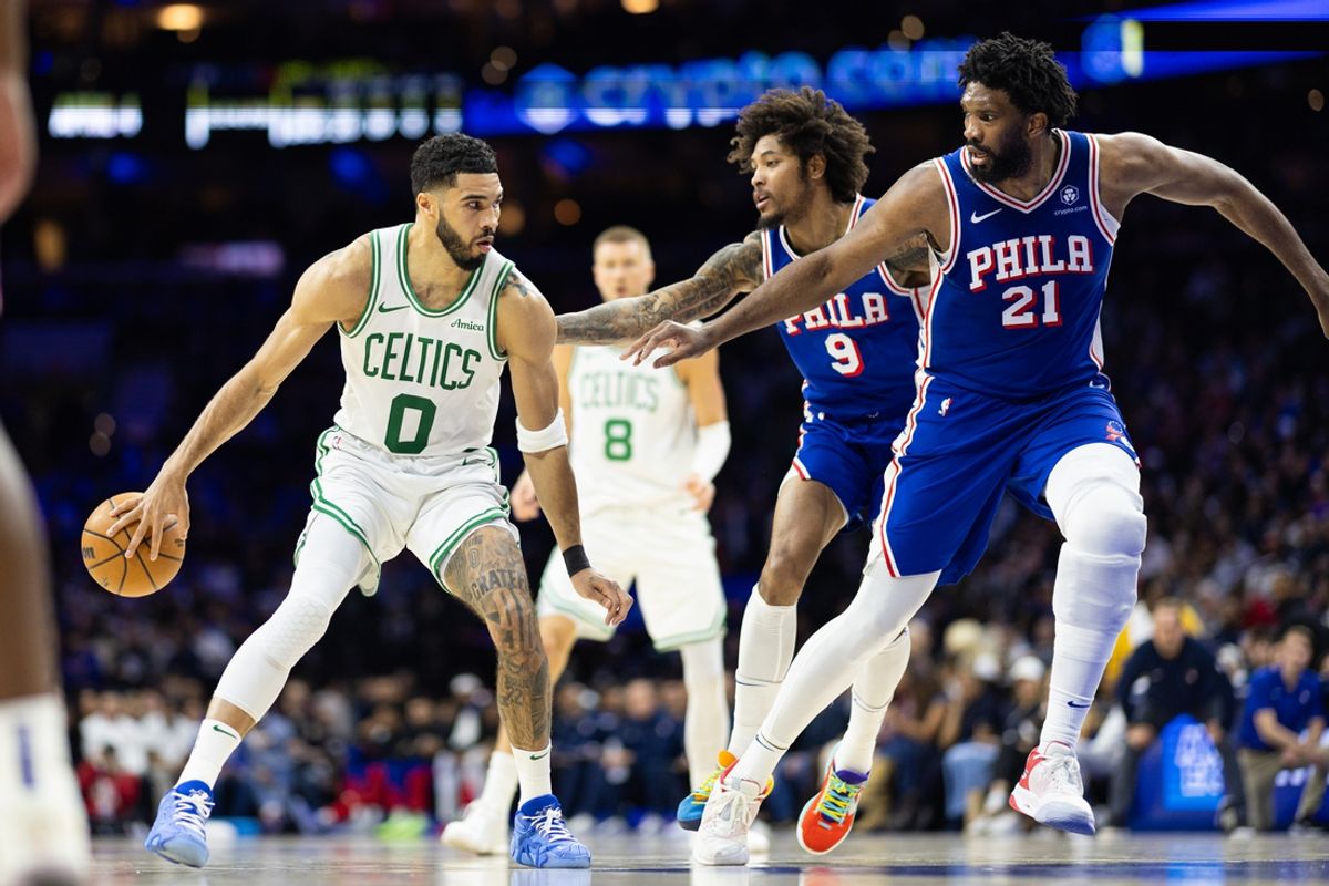 Feb 20, 2025; Philadelphia, Pennsylvania, USA; Boston Celtics forward Jayson Tatum (0) passes the ball back to center Kristaps Porzingis (8) in front of Philadelphia 76ers center Joel Embiid (21) and guard Kelly Oubre Jr. (9) during the second quarter at Wells Fargo Center. Mandatory Credit: Bill Streicher-Imagn Images