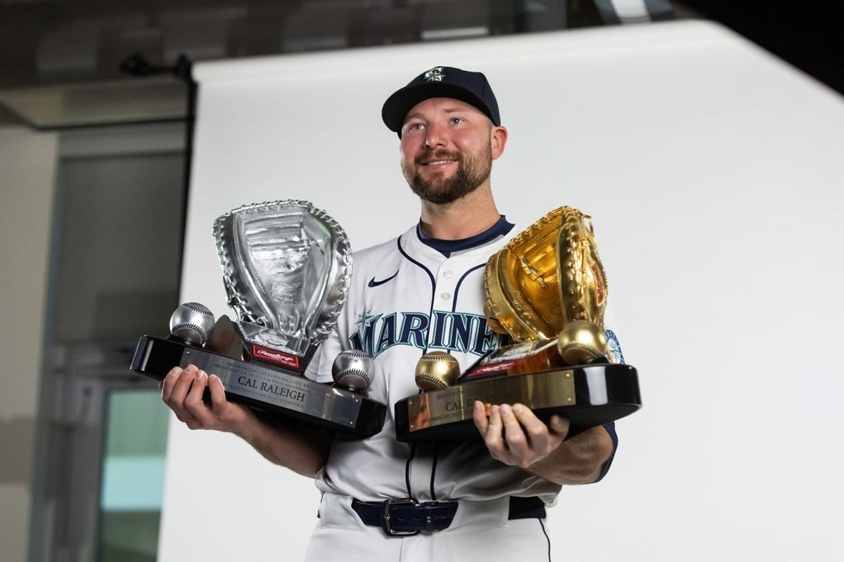 Feb 20, 2025; Peoria, AZ, USA; Seattle Mariners catcher Cal Raleigh poses for a portrait with his Rawlings Gold Glove and Platinum Glove trophies during media day at Peoria Sports Complex. Mandatory Credit: Mark J. Rebilas-Imagn Images