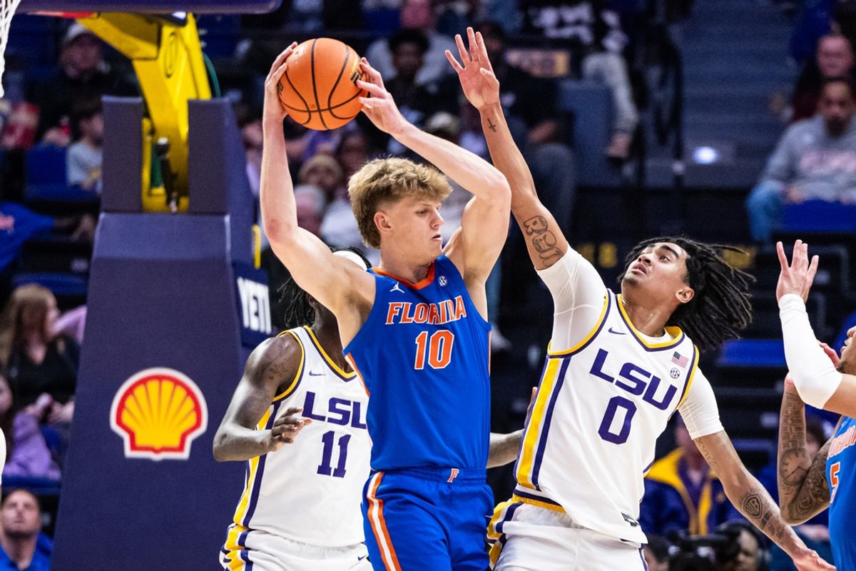 Feb 22, 2025; Baton Rouge, Louisiana, USA; Florida Gators forward Thomas Haugh (10) dribbles against LSU Tigers guard Vyctorius Miller (0) and forward Corey Chest (11) during the first half at Pete Maravich Assembly Center. Mandatory Credit: Stephen Lew-Imagn Images