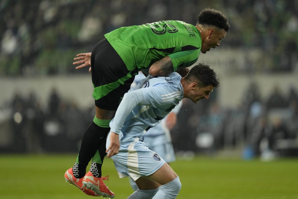 Feb 22, 2025; Austin, Texas, USA; Austin FC defender Julio Cascante (18) leaps on top of Sporting Kansas City midfielder Nemanja Radoja (6) during the first half at Q2 Stadium. Mandatory Credit: Scott Wachter-Imagn Images
