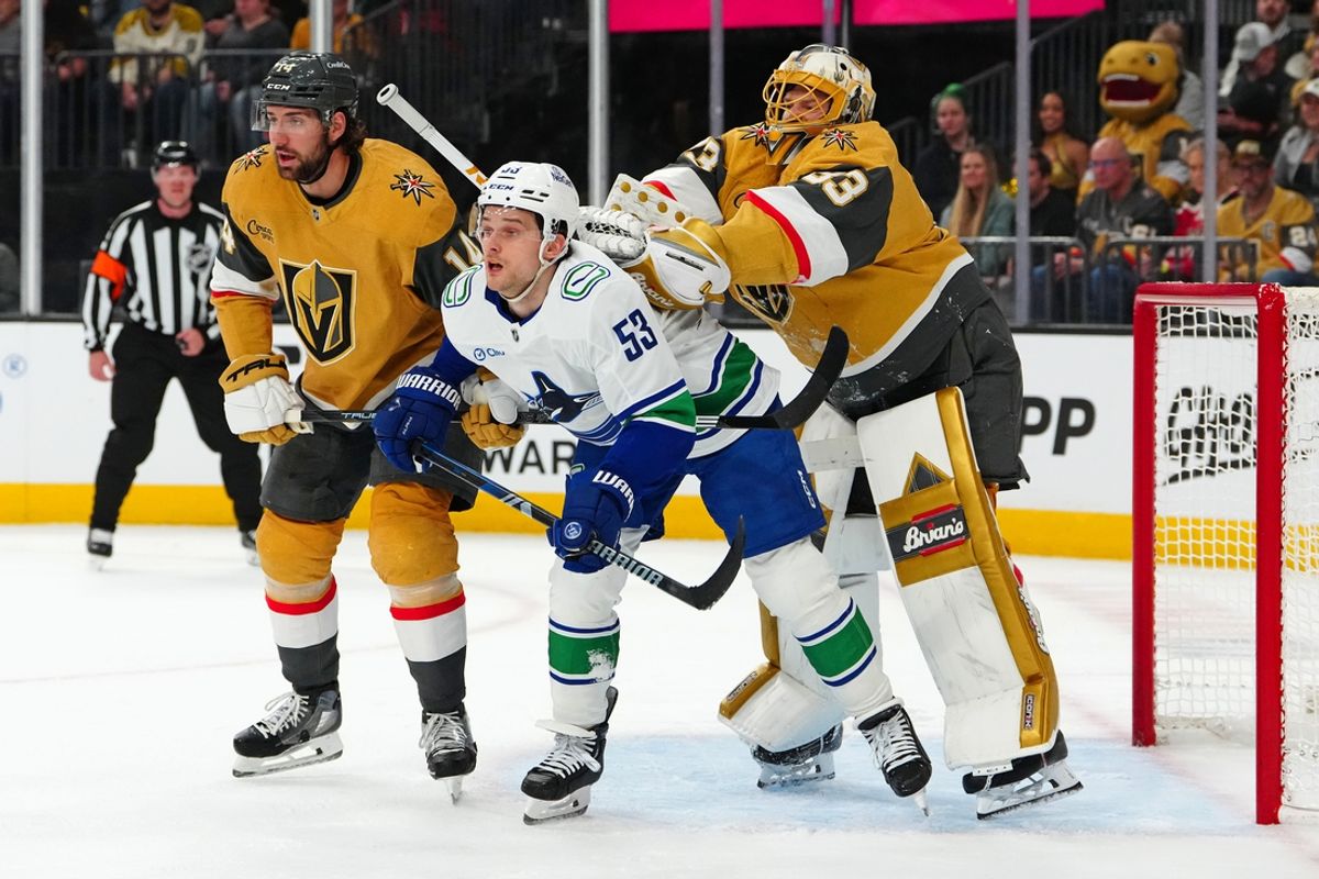 Feb 22, 2025; Las Vegas, Nevada, USA; Vegas Golden Knights goaltender Adin Hill (33) checks Vancouver Canucks center Teddy Blueger (53) beside Vegas Golden Knights defenseman Nicolas Hague (14) during the first period at T-Mobile Arena. Mandatory Credit: Stephen R. Sylvanie-Imagn Images