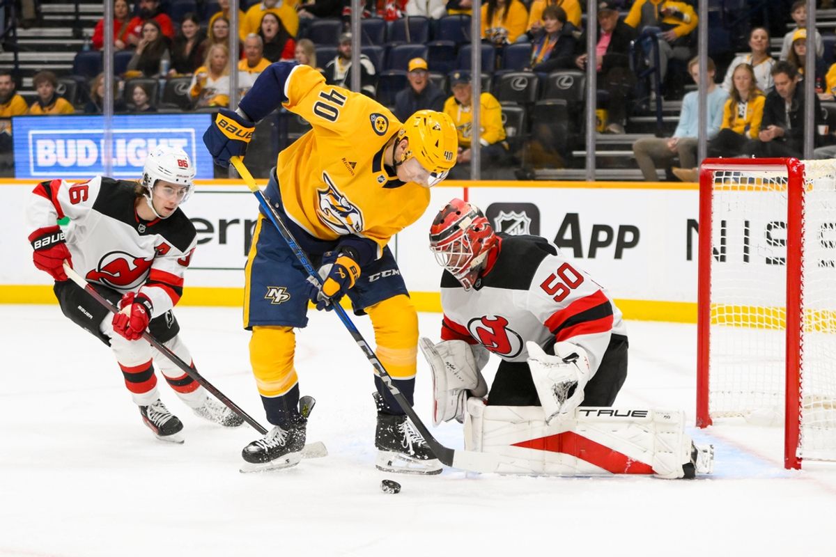 Feb 23, 2025; Nashville, Tennessee, USA;  New Jersey Devils goaltender Nico Daws (50) blocks the shot of Nashville Predators center Fedor Svechkiv (40) during the first half at Bridgestone Arena. Mandatory Credit: Steve Roberts-Imagn Images