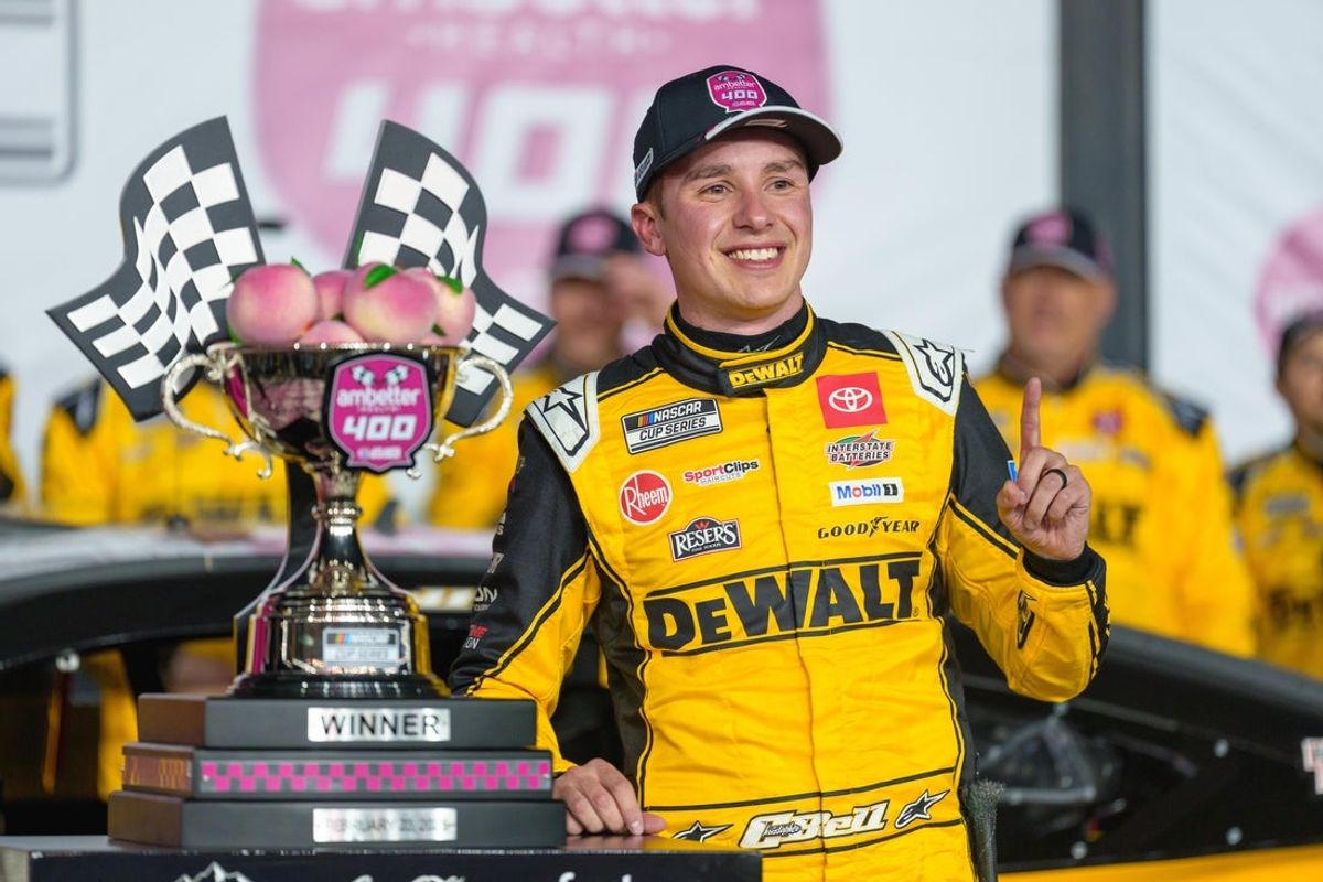 Feb 23, 2025; Hampton, Georgia, USA; Christopher Bell (20) poses with his trophy in Victory Lane after claiming a victory at Atlanta Motor Speedway. Mandatory Credit: Jason Allen-Imagn Images