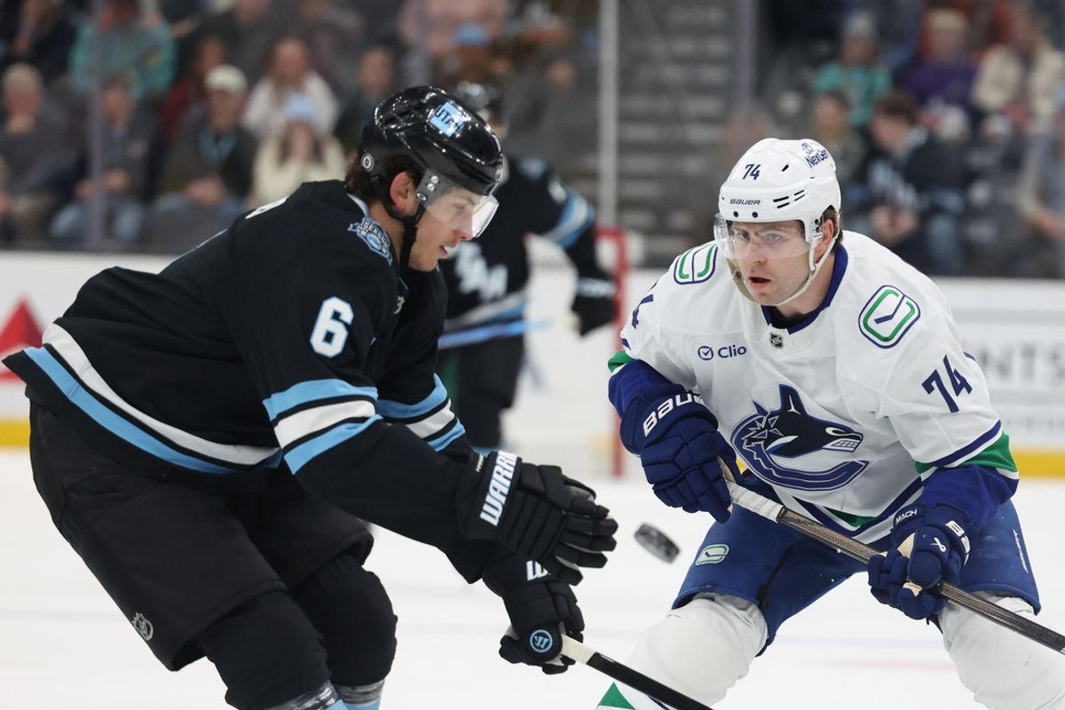 Feb 23, 2025; Salt Lake City, Utah, USA; Utah Hockey Club defenseman John Marino (6) and Vancouver Canucks left wing Jake DeBrusk (74) play the puck during the first period at Delta Center. Mandatory Credit: Rob Gray-Imagn Images