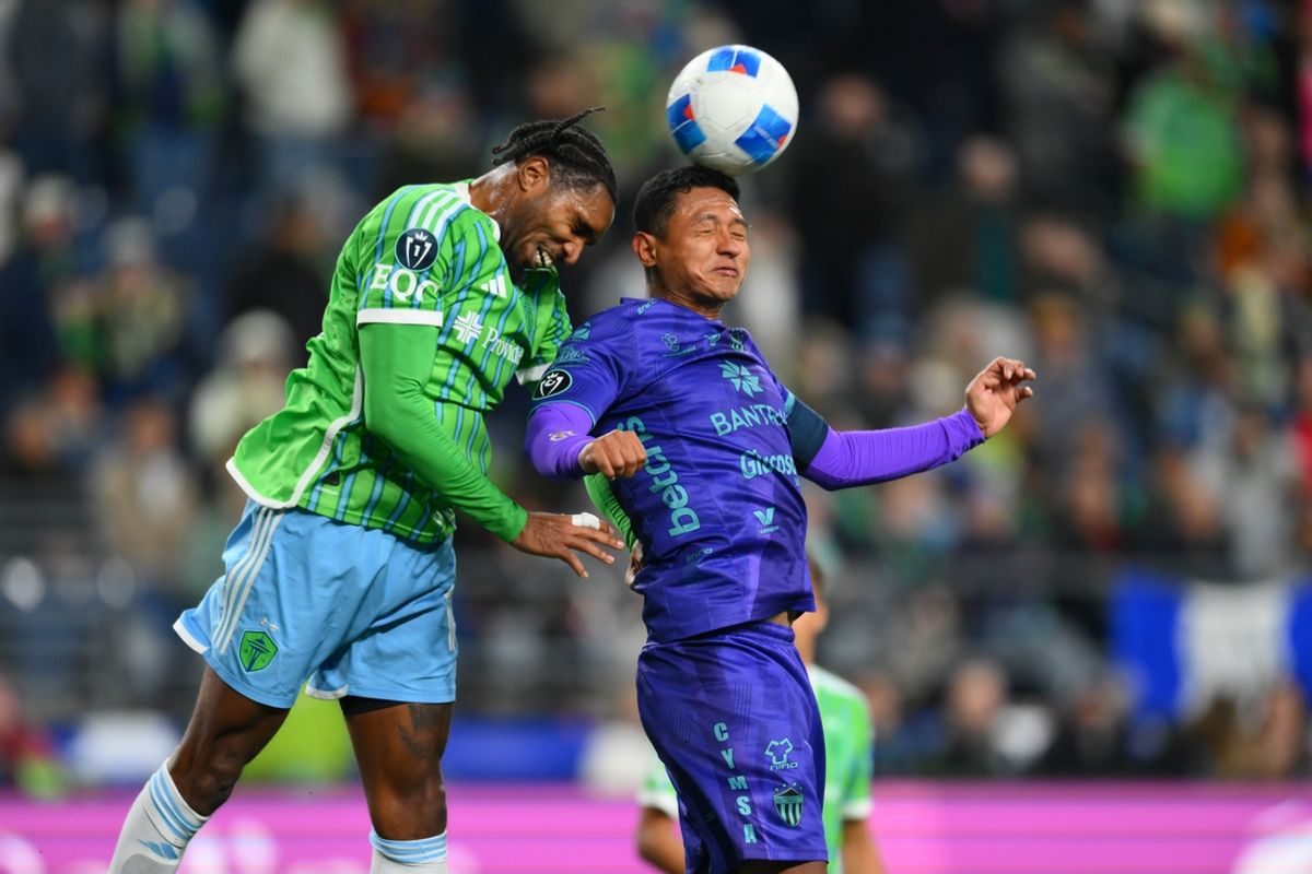 Feb 26, 2025; Seattle, Washington, USA; Antigua GFC defender Jose Agustin Ardon Castellanos (12) heads the ball in front of Seattle Sounders FC defender Jon Bell (15) during the second half at Lumen Field. Mandatory Credit: Steven Bisig-Imagn Images