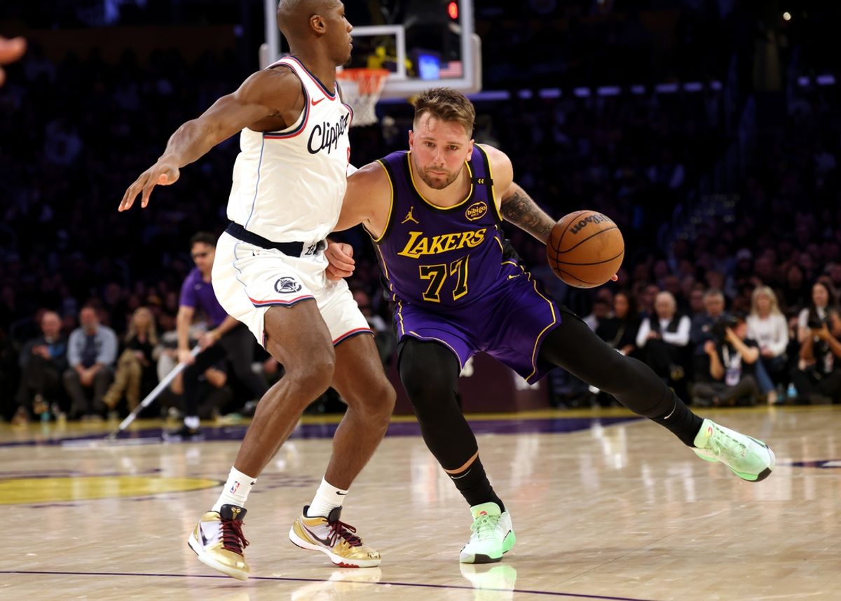 Feb 28, 2025; Los Angeles, California, USA; Los Angeles Lakers guard Luka Doncic (77) drives against LA Clippers guard Kris Dunn (8) during the fourth quarter at Crypto.com Arena. Mandatory Credit: Jason Parkhurst-Imagn Images