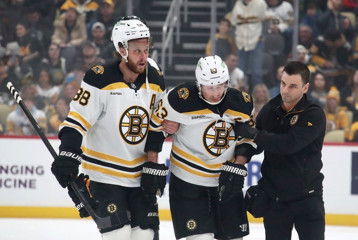 Mar 1, 2025; Pittsburgh, Pennsylvania, USA;  Boston Bruins left wing Brad Marchand (63) is helped from the ice by right wing David Pastrnak (88) and a team trainer after suffering an apparent injury against the Pittsburgh Penguins during the first period at PPG Paints Arena. Mandatory Credit: Charles LeClaire-Imagn Images