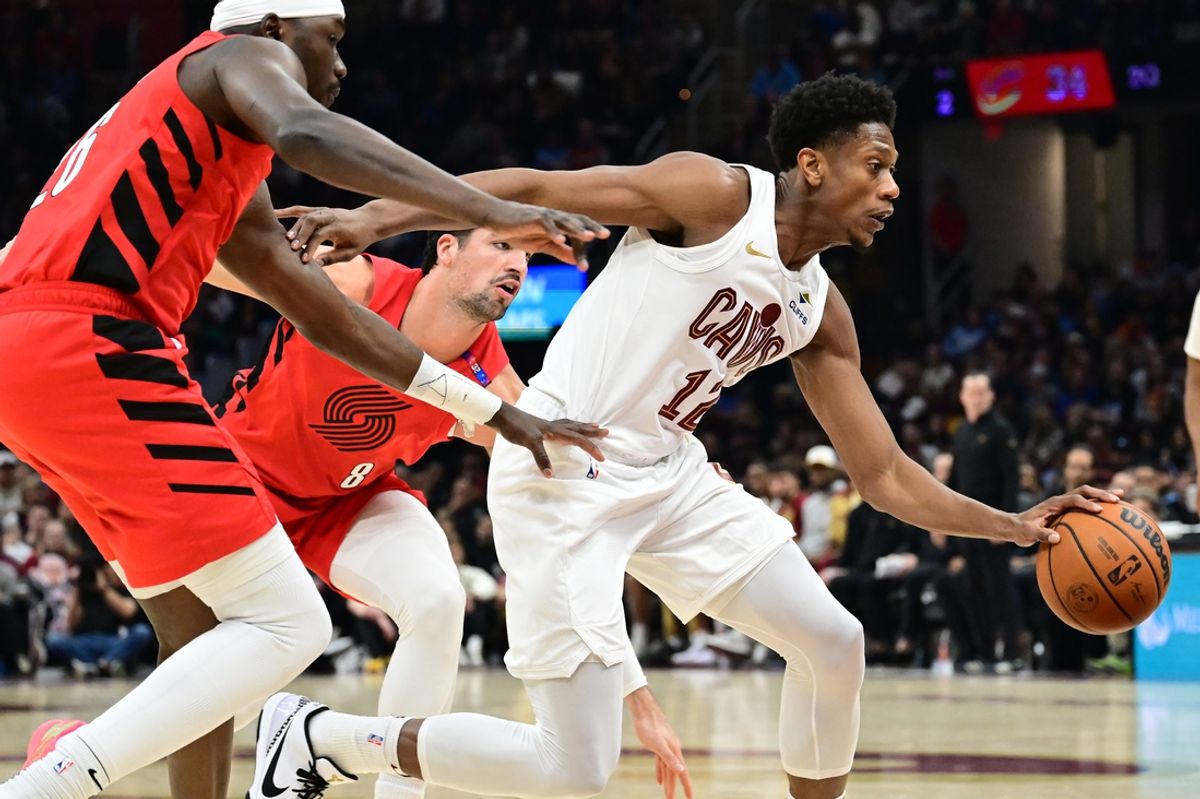 Mar 2, 2025; Cleveland, Ohio, USA; Cleveland Cavaliers forward De'Andre Hunter (12) drives to the basket against Portland Trail Blazers center Duop Reath (26) and forward Deni Avdija (8) during the first half at Rocket Arena. Mandatory Credit: Ken Blaze-Imagn Images