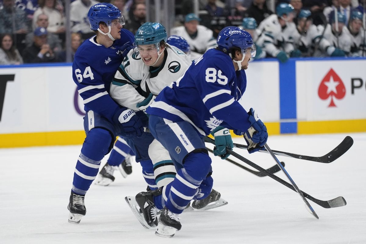 Mar 3, 2025; Toronto, Ontario, CAN; San Jose Sharks forward Macklin Celebrini (71) gets checked by Toronto Maple Leafs forward Nicholas Robertson (89) and forward David Kampf (64) during the second period at Scotiabank Arena. Mandatory Credit: John E. Sokolowski-Imagn Images