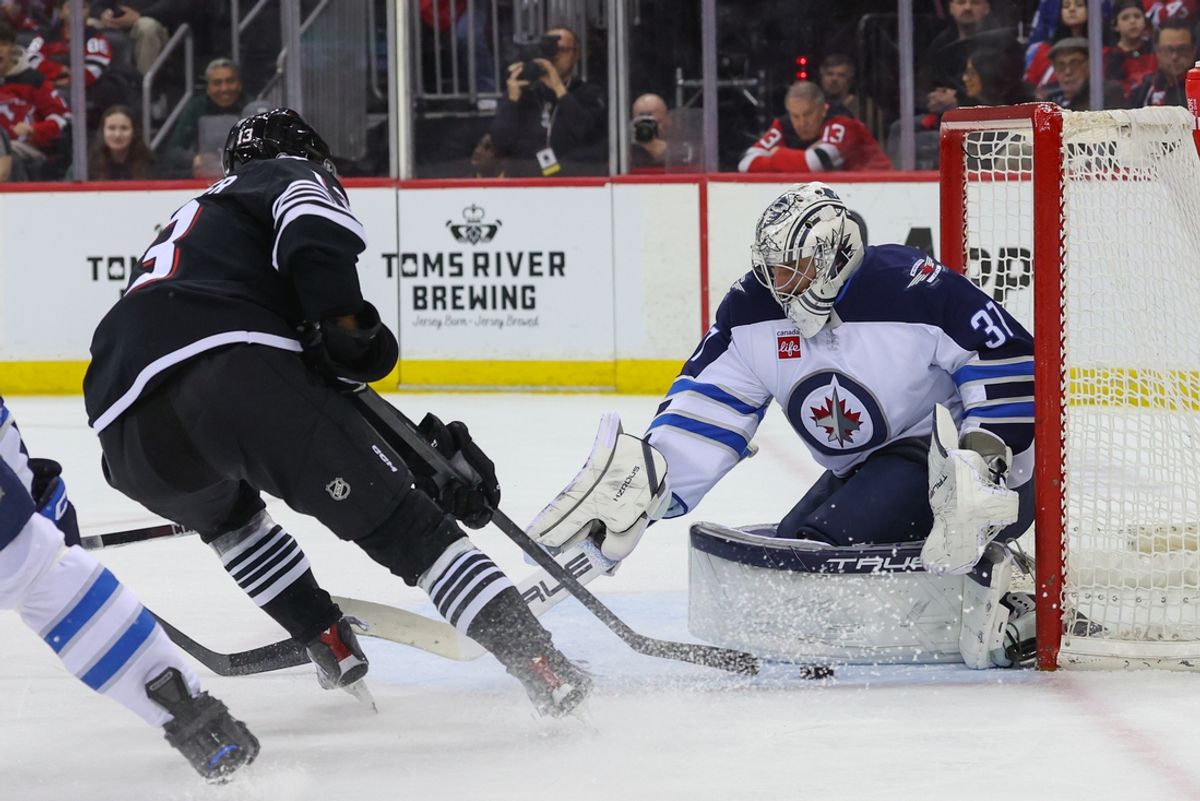 Mar 7, 2025; Newark, New Jersey, USA; Winnipeg Jets goaltender Connor Hellebuyck (37) makes a save on New Jersey Devils center Nico Hischier (13) during the second period at Prudential Center. Mandatory Credit: Ed Mulholland-Imagn Images
