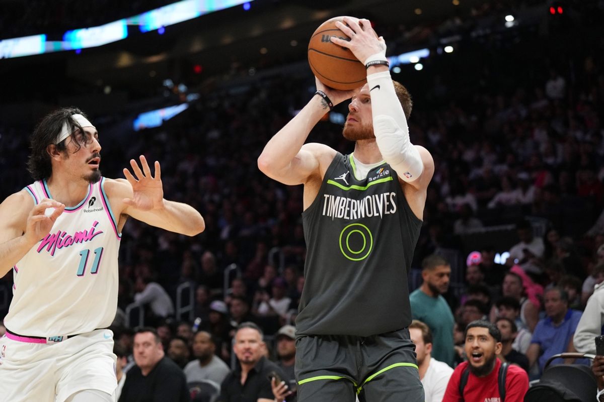 Mar 7, 2025; Miami, Florida, USA;  Minnesota Timberwolves guard Donte DiVincenzo (0) takes a three-point shot as Miami Heat guard Jaime Jaquez Jr. (11) defends during the second half at Kaseya Center. Mandatory Credit: Jim Rassol-Imagn Images